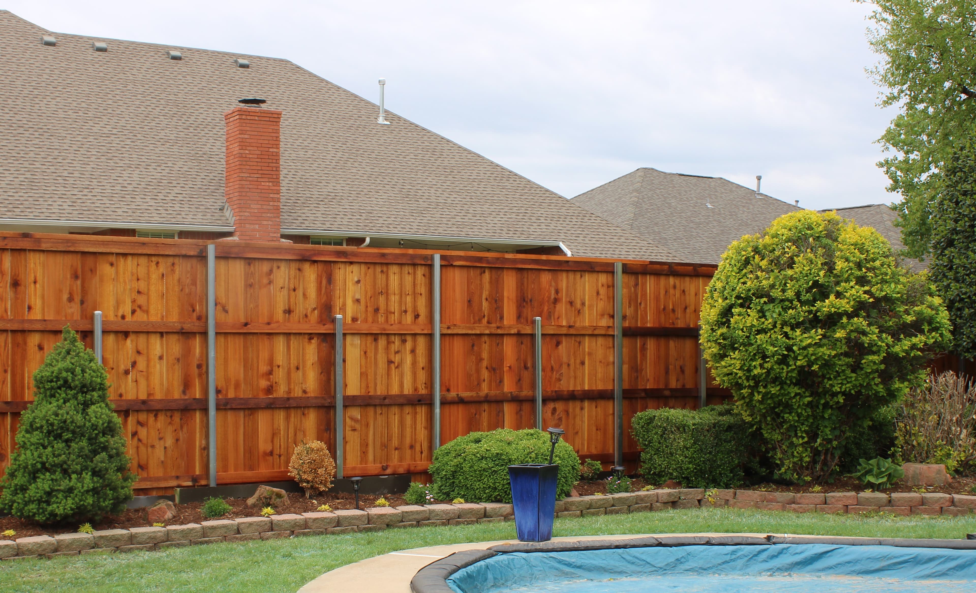 Freshly stained cedar privacy fence around a backyard pool in Oklahoma City