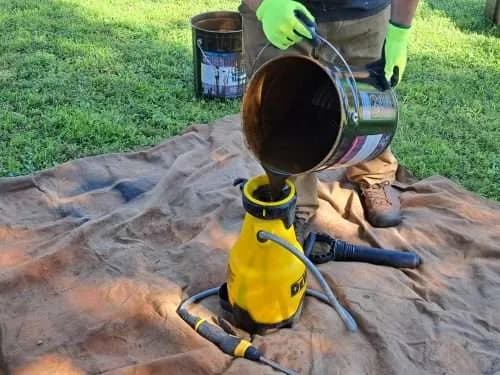 Pouring fence stain into a pump sprayer before staining a fence in Oklahoma City